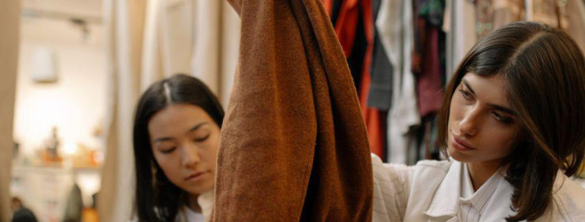Une dame examine une veste dans un magasin de mode et vêtements.